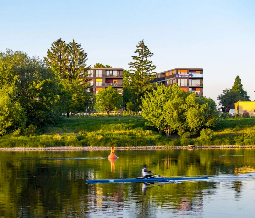Die Elbe mit einem Ruderer auf dem Wasser und dem Wohnprojekt Marina Garden im Hintergrund in Dresden
